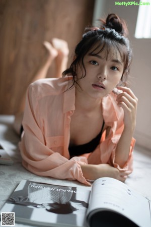 A naked asian woman sitting on the floor in a black underwear.