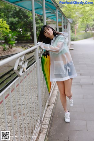 A woman leaning against a tree holding an umbrella.