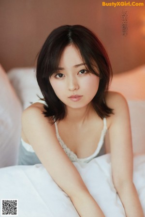 A woman laying on top of a bed next to pillows.