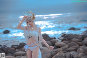 A woman in a white dress standing on a beach.