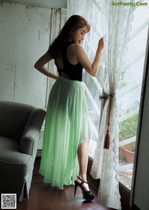 A woman sitting on a chair in front of a window.