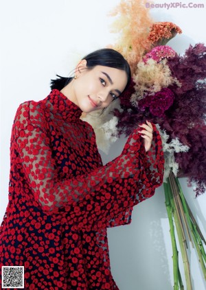 A woman in a red dress holding a red flower.