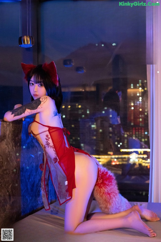 A woman in a red lingerie sitting on a window sill.