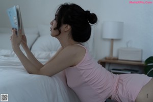 a woman in a pink top and shorts standing on a bed