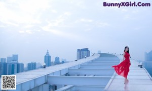 A woman in a red dress standing on top of a building.