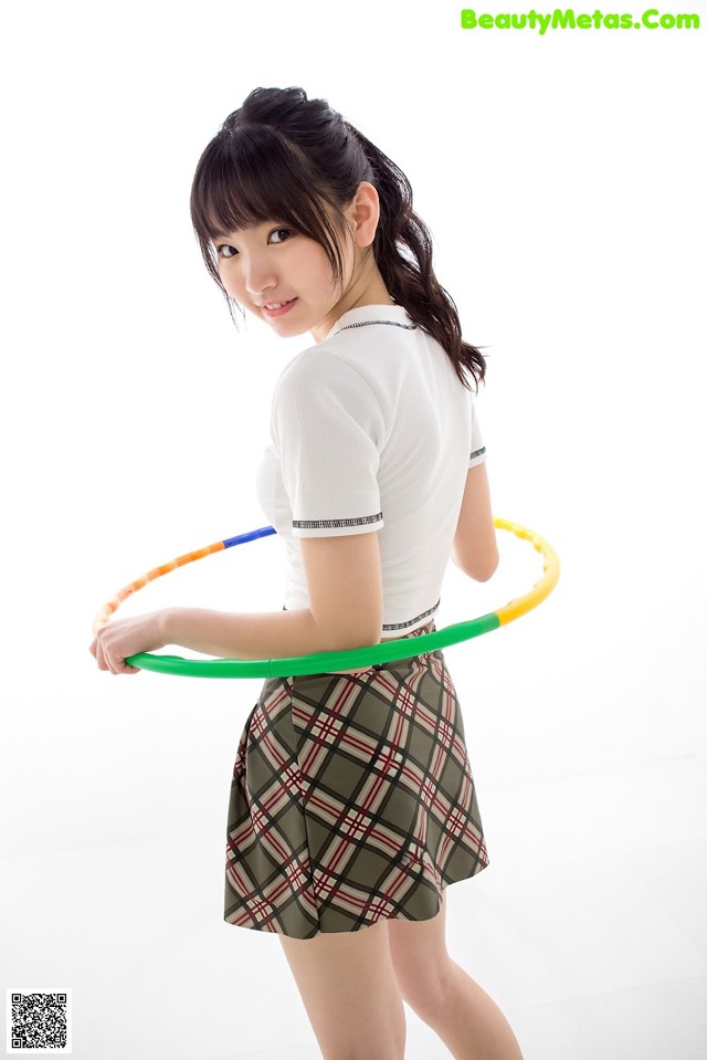 A young woman holding a hula hoop in her hands.