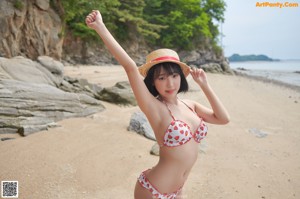 A woman in a red and white bikini sitting on a rock.