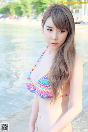 A woman in a black bikini standing on a beach.