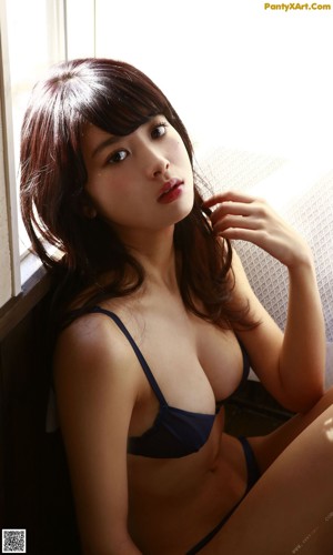 A woman in a blue bikini sitting on the floor.