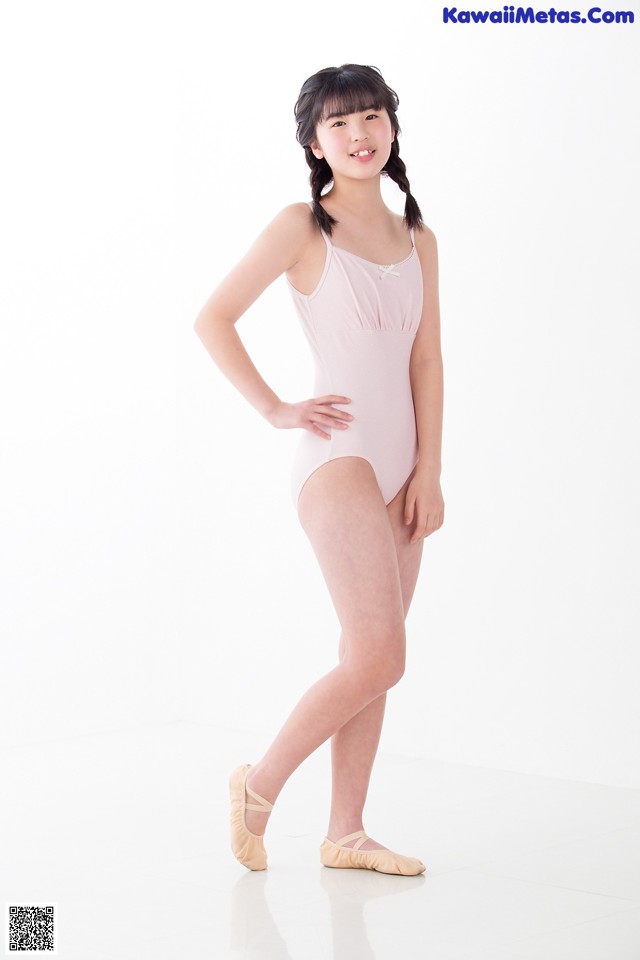 A young girl in a pink leotard and pointe shoes.