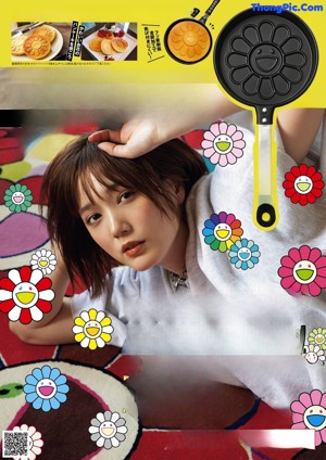 A woman standing in front of a wall covered in colorful flowers.