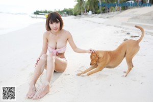 A woman in a pink bikini standing on a beach.