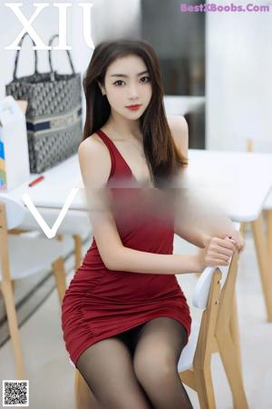 A woman in a red dress sitting on a white chair.