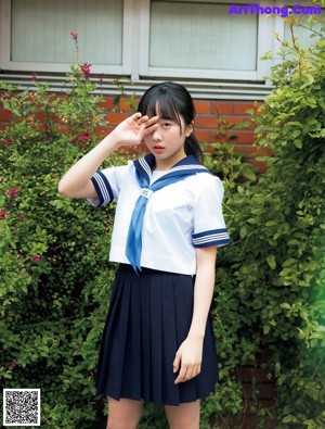 A woman in a school uniform holding a soccer ball.