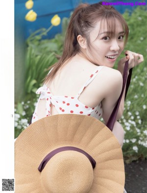 A woman sitting on a wooden bench wearing a straw hat.