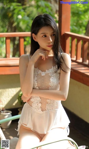 A woman in a white dress sitting on a chair.