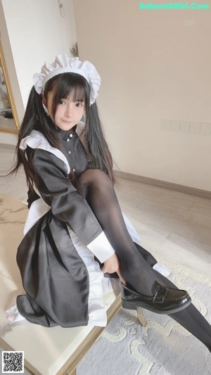 a woman in a maid outfit sitting on a bed