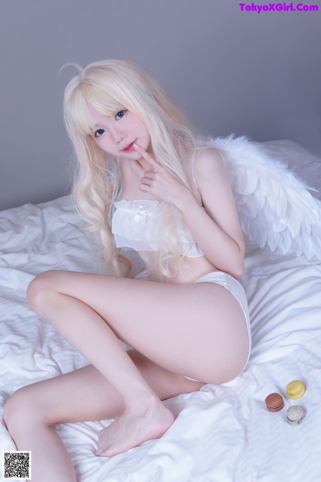 A woman in a white lingerie sitting on a bed.