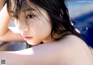 A woman in a white lingerie sitting on the edge of a pool.