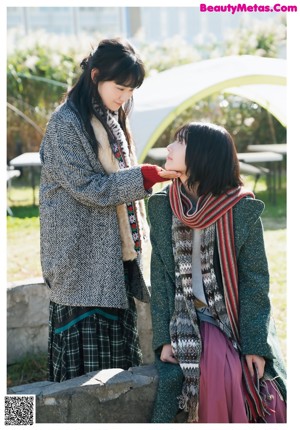 A woman in a blue shirt and green skirt holding hands with a child.