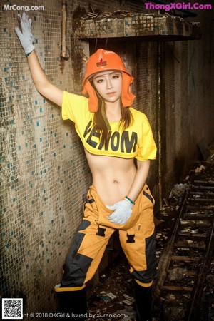 A woman wearing a white hard hat and a blue top.