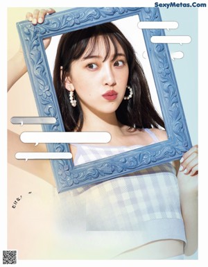 A woman in a blue dress and a straw hat is posing for a magazine.