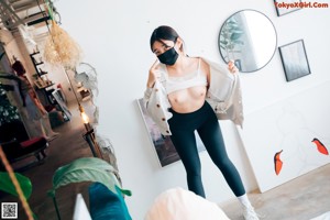 A woman sitting on top of a bed next to a mirror.