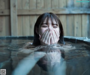 A woman standing in front of a hot tub with purple flowers.