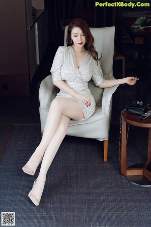 A woman in a silver dress sitting on a couch.