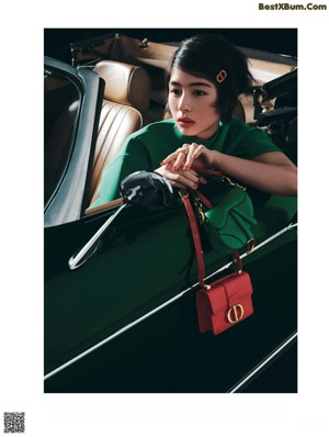 A woman sitting in the driver's seat of a green car.