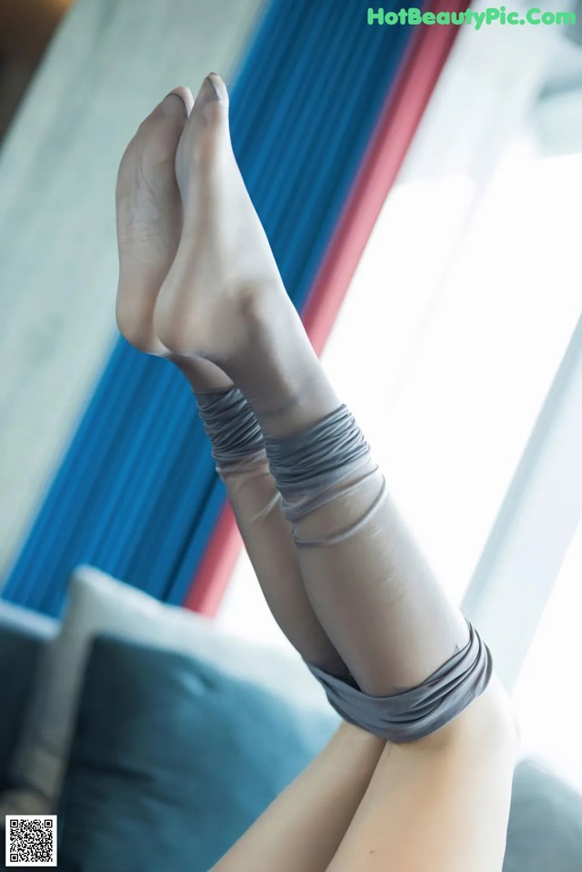 A woman's legs in gray stockings on a couch.