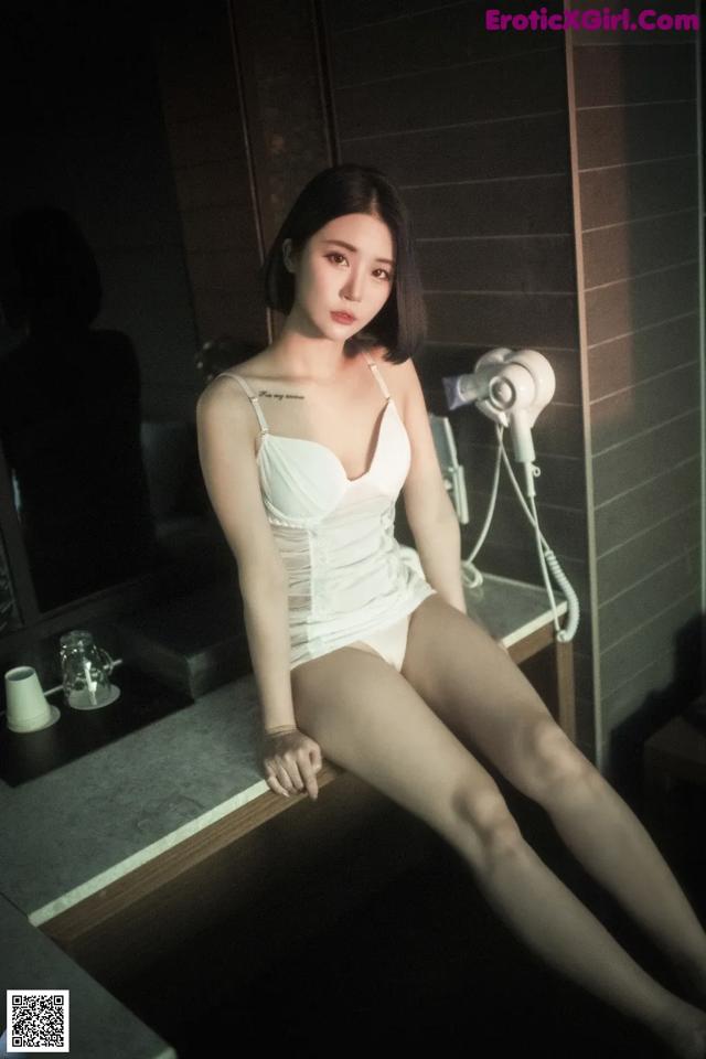 A woman sitting on a counter in a bathroom.