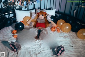A woman in a cat costume holding a pumpkin.