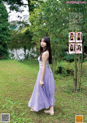 A woman in a long purple skirt standing in the grass.