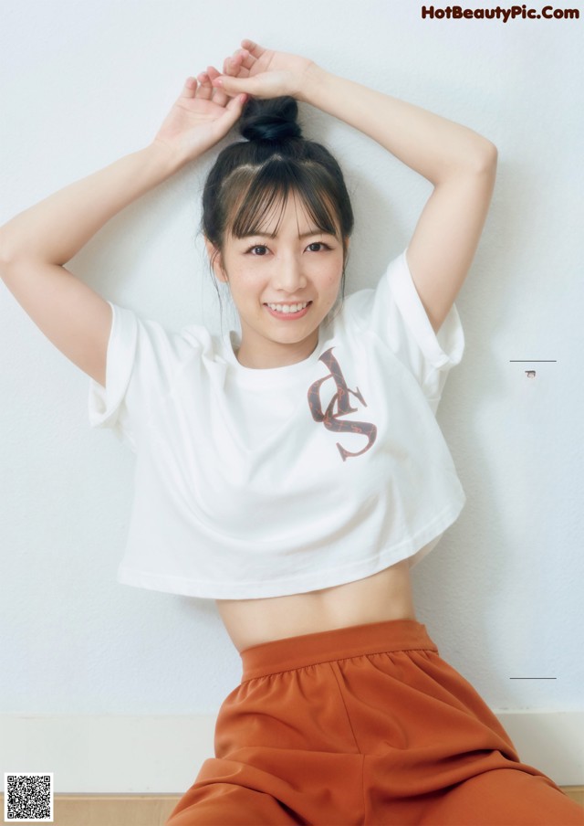 A woman in a white shirt and brown pants posing for a magazine.