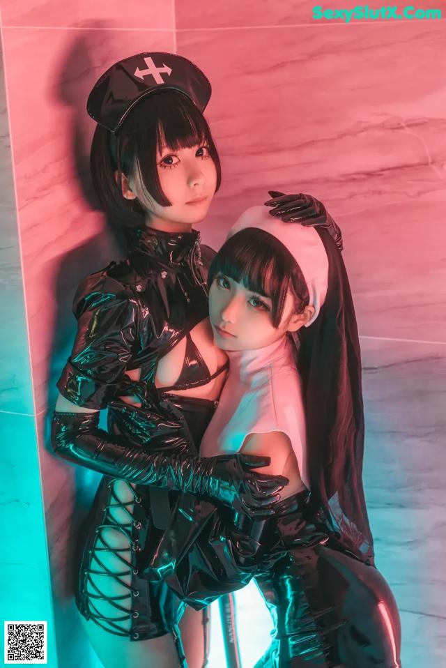 A couple of women dressed in latex posing for a picture.