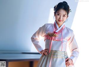 A woman in a blue and white hanbok poses for a picture.