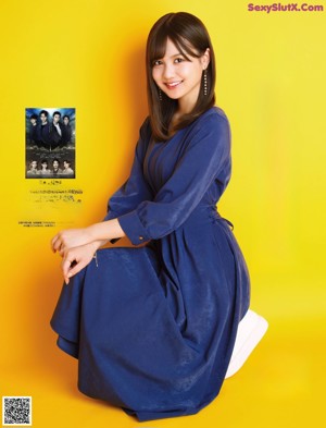 A woman with long brown hair and bangs is posing for a magazine.