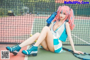 A woman with pink hair sitting on a tennis court.